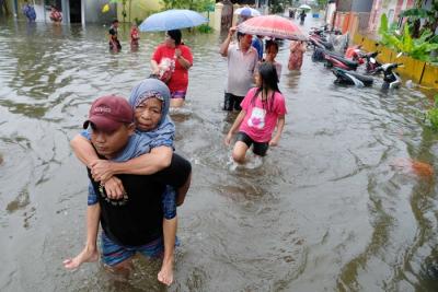 Sejumlah warga melewati banjir untuk mengungsi ketempat yang lebih aman di Makassar, Selasa (7/12/2021).