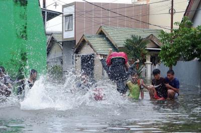 Warga menerobos banjir di Kompleks Perumahan Swadaya Mas, Keluarahan Batua, Kecamatan Manggala, Makassar, Sulawesi Selatan, Selasa (7/12/2021).