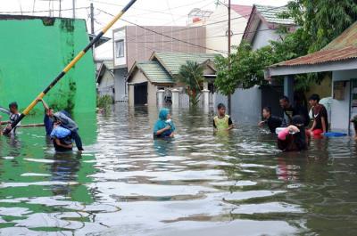 Warga menerobos banjir di Kompleks Perumahan Swadaya Mas, Keluarahan Batua, Kecamatan Manggala, Makassar, Sulawesi Selatan, Selasa (7/12/2021).