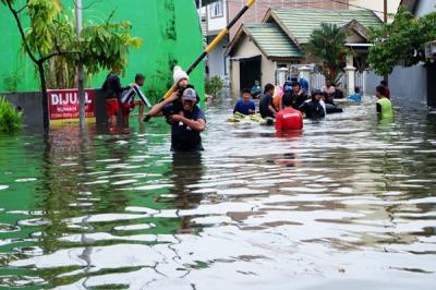 Warga menerobos banjir di Kompleks Perumahan Swadaya Mas, Keluarahan Batua, Kecamatan Manggala, Makassar, Sulawesi Selatan, Selasa (7/12/2021).