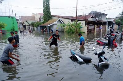 Warga menerobos banjir di Kompleks Perumahan Swadaya Mas, Keluarahan Batua, Kecamatan Manggala, Makassar, Sulawesi Selatan, Selasa (7/12/2021).
