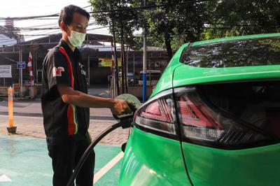 Petugas menaruh kontak tusuk ke kendaraan untuk melakukan pengisian daya di Stasiun Pengisian Kendaraan Listrik Umum (SPKLU) di Kawasan MT Haryono.