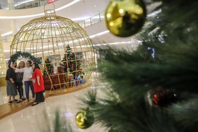 Pengunjung berfoto dengan latar belakang instalasi Golden Giant Christmas Tree di Atrium Pusat Perbelanjaan Senayan City, Jakarta Pusat, Selasa (14/12/2021).