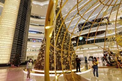 Pengunjung berfoto dengan latar belakang instalasi Golden Giant Christmas Tree di Atrium Pusat Perbelanjaan Senayan City, Jakarta Pusat, Selasa (14/12/2021).