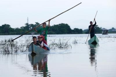 Sejumlah murid menggunakan perahu saat melintasi area persawahan yang terendam banjir di Kelurahan Tamangapa, Makassar, Rabu (15/12/2021).