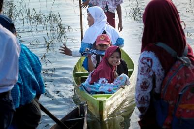 Sejumlah murid menggunakan perahu saat melintasi area persawahan yang terendam banjir di Kelurahan Tamangapa, Makassar, Rabu (15/12/2021).
