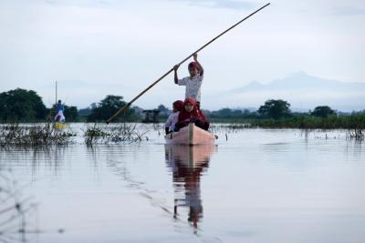 Sejumlah murid menggunakan perahu saat melintasi area persawahan yang terendam banjir di Kelurahan Tamangapa, Makassar, Rabu (15/12/2021).