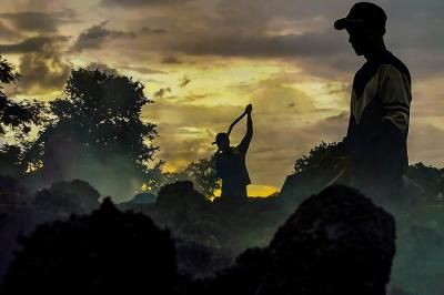 Potret Para pekerja sedang menggoreng campuran pasir dan campuran aspal secara manual di lahan kosong, Bandung, Jawa Barat, Minggu (19/12/2021).