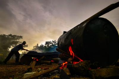 Potret Para pekerja sedang menggoreng campuran pasir dan campuran aspal secara manual di lahan kosong, Bandung, Jawa Barat, Minggu (19/12/2021).