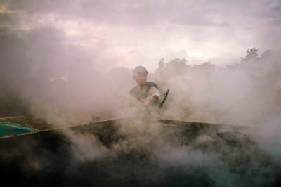 Potret Para pekerja sedang menggoreng campuran pasir dan campuran aspal secara manual di lahan kosong, Bandung, Jawa Barat, Minggu (19/12/2021).