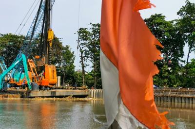 Pekerja dengan alat berat saat menyelesaikan pemasangan dinding turap atau sheetpile di aliran kali PIK, Jakarta Utara, Selasa (21/12/2021).