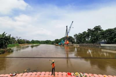 Pekerja dengan alat berat saat menyelesaikan pemasangan dinding turap atau sheetpile di aliran kali PIK, Jakarta Utara, Selasa (21/12/2021).