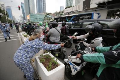 Sejumlah perserta aksi yang tergabung dalam Forum Kader Bela Negara DKI Jakarta menggelar aksi membagikan bunga dan masker kepada pengguna jalan.