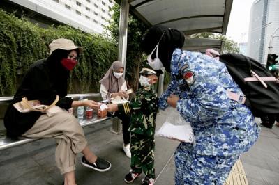 Sejumlah perserta aksi yang tergabung dalam Forum Kader Bela Negara DKI Jakarta menggelar aksi membagikan bunga dan masker kepada pengguna jalan.