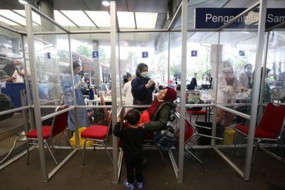 Petugas kesehatan melakukan tes swab PCR pada seorang anak di Stasiun Pasar Senen, Jakarta, Kamis (23/12/2021).