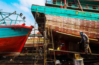 Aktivitas pekerja saat memperbaiki kapal di sebuah galangan kapal kawasan Muara Angke, Jakarta Utara, Rabu (22/12/2021).
