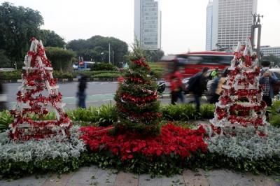 Seorang wanita menghias pohon Natal di kawasan Bundaran HI, Jakarta, Kamis (23/12/2021).