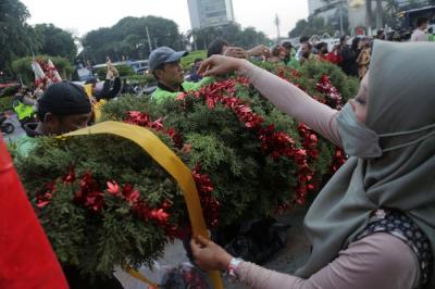 Seorang wanita menghias pohon Natal di kawasan Bundaran HI, Jakarta, Kamis (23/12/2021).