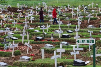 Warga menabur bunga di atas makam keluarganya saat ziarah di Tempat Pemakaman Khusus Covid-19, Rorotan, Jakarta Utara, Sabtu (25/12/2021).