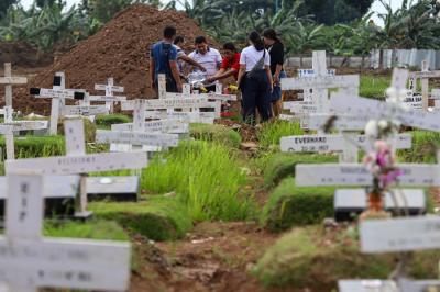 Warga menabur bunga di atas makam keluarganya saat ziarah di Tempat Pemakaman Khusus Covid-19, Rorotan, Jakarta Utara, Sabtu (25/12/2021).