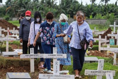Warga menabur bunga di atas makam keluarganya saat ziarah di Tempat Pemakaman Khusus Covid-19, Rorotan, Jakarta Utara, Sabtu (25/12/2021).