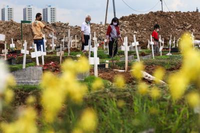 Warga menabur bunga di atas makam keluarganya saat ziarah di Tempat Pemakaman Khusus Covid-19, Rorotan, Jakarta Utara, Sabtu (25/12/2021).