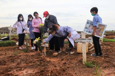 Warga menabur bunga di atas makam keluarganya saat ziarah di Tempat Pemakaman Khusus Covid-19, Rorotan, Jakarta Utara, Sabtu (25/12/2021).