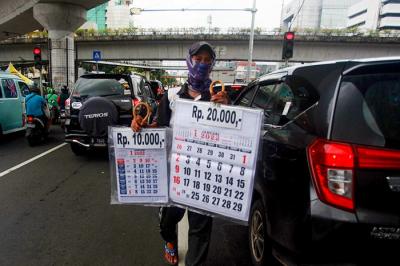 Pedagang musiman menawarkan kalender 2022 kepada pengendara di lampu merah kawasan, Jakarta Pusat, Selasa (28/12/2021).