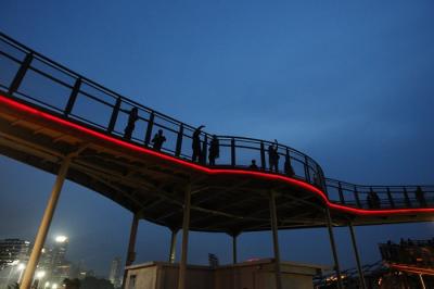 Pengunjung berswafoto dengan latar belakang lansekap perkotaan di Skywalk, Senayan Park, Jakarta, Rabu (29/12/2021).