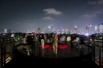 Pengunjung berswafoto dengan latar belakang lansekap perkotaan di Skywalk, Senayan Park, Jakarta, Rabu (29/12/2021).