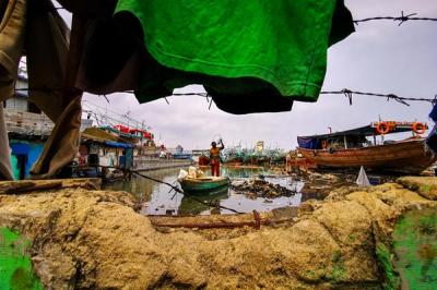 Warga menggunakan perahu kecil mencari barang-barang yang dapat dijual di Muara Angke, Jakarta Utara, Senin (3/1/2022).