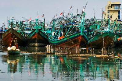 Warga menggunakan perahu kecil mencari barang-barang yang dapat dijual di Muara Angke, Jakarta Utara, Senin (3/1/2022).