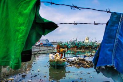 Warga menggunakan perahu kecil mencari barang-barang yang dapat dijual di Muara Angke, Jakarta Utara, Senin (3/1/2022).