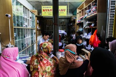 Penjual seragam sekolah saat melayani pembeli di Pasar Embrio, Kampung Makasar, Jakarta Timur, Minggu (2/1/2022).