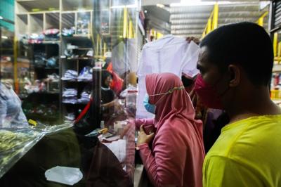 Penjual seragam sekolah saat melayani pembeli di Pasar Embrio, Kampung Makasar, Jakarta Timur, Minggu (2/1/2022).