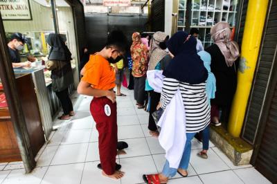 Penjual seragam sekolah saat melayani pembeli di Pasar Embrio, Kampung Makasar, Jakarta Timur, Minggu (2/1/2022).