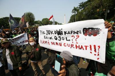 Sejumlah pengemudi ojek online membentangkan spanduk saat aksi unjuk rasa di Jakarta, Rabu (5/1/2022).