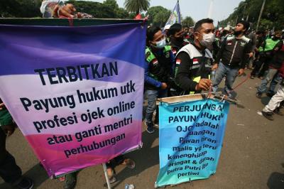 Sejumlah pengemudi ojek online membentangkan spanduk saat aksi unjuk rasa di Jakarta, Rabu (5/1/2022).