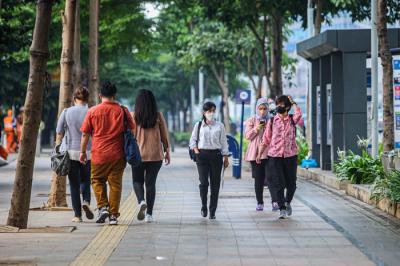 Pekerja melintasi jalur pedestrian di kawasan Sudirman saat jam pulang kerja di Jakarta, Rabu (5/1/2022).