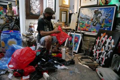Pengrajin Dwiyono melukis dengan memanfaatkan limbah sampah plastik di sanggar kerja miliknya di Jakarta, Sabtu (8/1/2022).