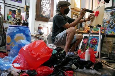 Pengrajin Dwiyono melukis dengan memanfaatkan limbah sampah plastik di sanggar kerja miliknya di Jakarta, Sabtu (8/1/2022).