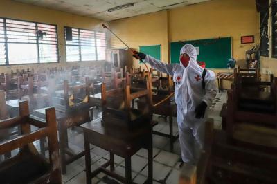 Petugas Palang Merah Indonesia (PMI) melakukan penyemprotan disinfektan pada ruang laboratorium di SMP Negeri 43, Jakarta Selatan, Kamis (20/1/2022).