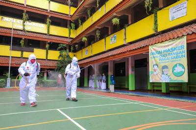 Petugas Palang Merah Indonesia (PMI) melakukan penyemprotan disinfektan pada ruang laboratorium di SMP Negeri 43, Jakarta Selatan, Kamis (20/1/2022).