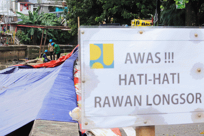 Sejumlah pekerja memperbaiki jalan yang ambles di Jalan Inspeksi Kali Ciliwung, Senen, Jakarta Pusat, Sabtu (5/2/2022).