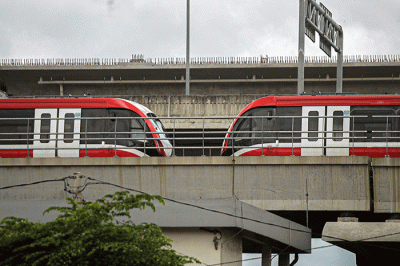 Pengendara sepeda motor melintasi kereta Light Rail Transit (LRT) Jabodebek yang diparkir di kawasan Jakasampurna, Kota Bekasi, Jawa Barat, Minggu (6/2/2022).