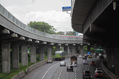Pengendara sepeda motor melintasi kereta Light Rail Transit (LRT) Jabodebek yang diparkir di kawasan Jakasampurna, Kota Bekasi, Jawa Barat, Minggu (6/2/2022).