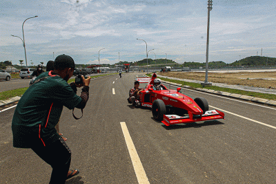 Michael Latip pembuat replika mobil balap F1 saat berpose layaknya pembalap di kawasan Sirkuit Mandalika, Lombok Tengah, NTB, Minggu (13/2/2022).