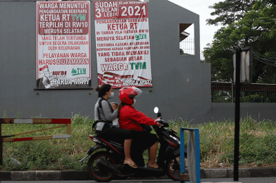 Warga melintasi spanduk meminta pelantikan RT di Meruya di Perumahan Taman Villa Meruya (TMV) Meruya Selatan, Kembangan, Jakarta Barat, Sabtu (26/2/2022).