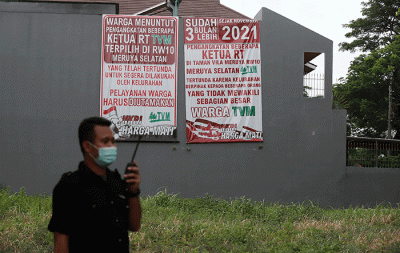 Warga melintasi spanduk meminta pelantikan RT di Meruya di Perumahan Taman Villa Meruya (TMV) Meruya Selatan, Kembangan, Jakarta Barat, Sabtu (26/2/2022).
