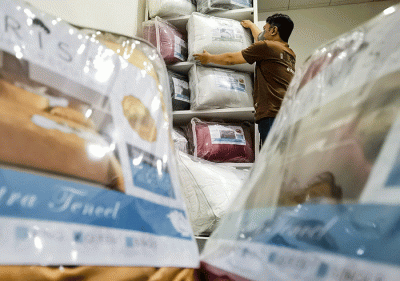 Penjual menata barang dagangannya berupa produk bahan sprei perlengkapan tempat tidur yang dipasarkan melalui online di toko orisa bedding, Jakarta Selatan.